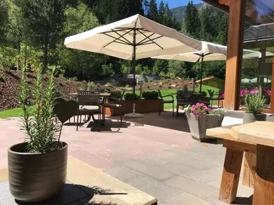 a patio with an umbrella and tables and chairs at Hotel Arnaria in Ortisei