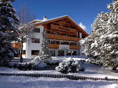 a large building in the snow with trees at Hotel Arnaria in Ortisei