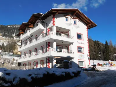 a large white building with snow on the ground at Ciasa Weiss in Vigo di Fassa