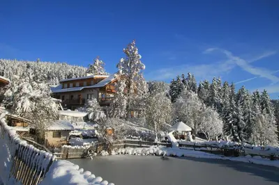 a house covered in snow next to a lake at Unterpfaffstall-Hof in Collalbo