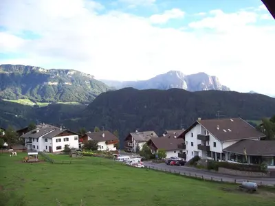 a town with houses and cars on a street with mountains at Mairhof in Laion