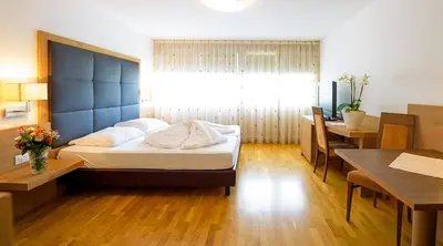 a bedroom with a bed and a desk and a table at Villa Residence Franziskus in Tirolo