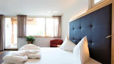 a bedroom with a large bed with a blue headboard at Villa Residence Franziskus in Tirolo