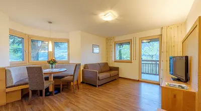 a living room with a table and a couch and a television at Villa Residence Franziskus in Tirolo