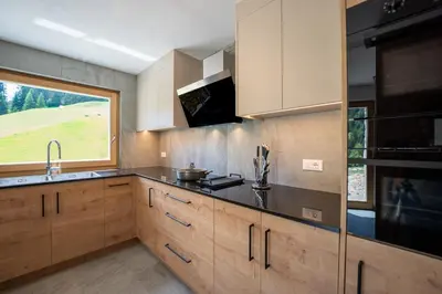 a kitchen with wooden cabinets and a large window at Chalet Fisti in La Villa