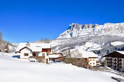 a village covered in snow with a mountain in the background at Chalet Fisti in La Villa