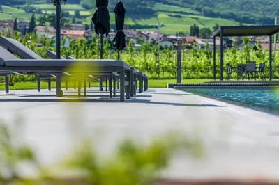 a pool with benches and chairs next to the water at Ferienwohnungen Zwerger Reinhold in Termeno