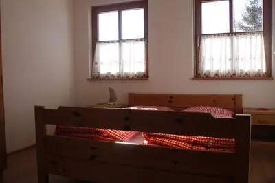 a bedroom with two windows and a bed with red pillows at Le Maier in San Vigilio Di Marebbe