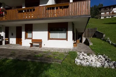 a house with a porch and a bench in the yard at Ca' Milijera in Cortina dʼAmpezzo