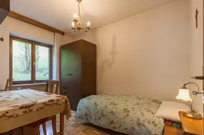 a bedroom with a bed and a table and a window at Casa Elena in Canale dʼAgordo