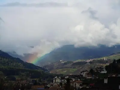 a rainbow in the middle of a mountain with a city at Appartamento Casa Fia per gruppi e famiglie in Tesero