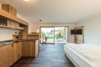 a bedroom with a bed and a kitchen with a sink at Weingut Moser Apartments in Caldaro