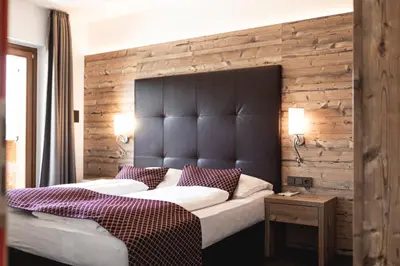 a bedroom with a large bed with a wooden wall at Hotel Der Heinrichshof in Lagundo