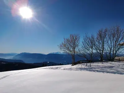 a snow covered hill with the sun in the sky at Spitalerhof Apartment & Sauna in Verano