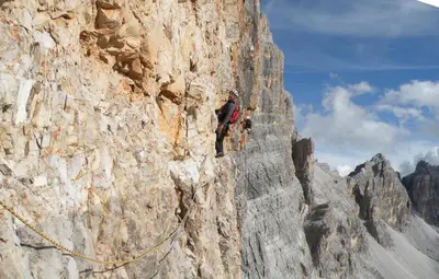a man is climbing on a rocky mountain at Hotel Garni Ongaro in Selva di Cadore