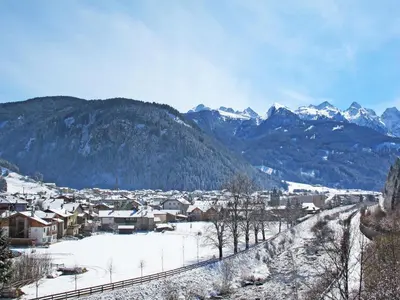 a town with snow covered mountains and a train at Apartment Garibaldi by Interhome in Predazzo