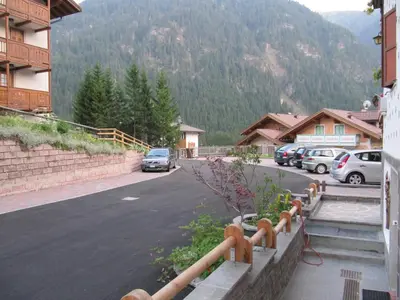 a yard with a playground and a house with parked cars at Garnì Villa Cecilia in Mazzin