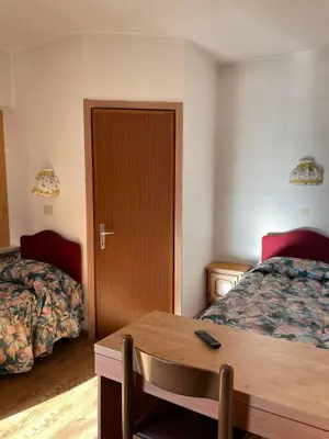 a hotel room with two beds and a table at Garnì Villa Cecilia in Mazzin