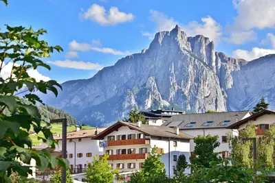a mountain towering over a town with buildings and trees at Apartment Gertrud in Castelrotto