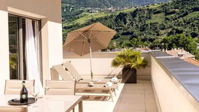 a balcony with a table and chairs and an umbrella at City Hotel Merano in Merano