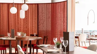a restaurant with tables and chairs and red curtains at City Hotel Merano in Merano