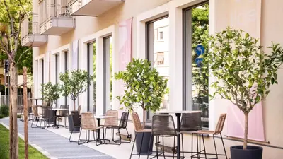 a row of tables and chairs on a sidewalk with trees at City Hotel Merano in Merano