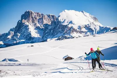 two people on skis on a snow covered mountain at Merlhof in Fiè