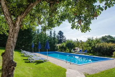 a swimming pool with lounge chairs and umbrellas at Merlhof in Fiè