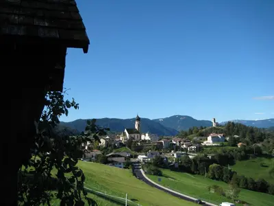 a small town on a hill with mountains in the background at Merlhof in Fiè