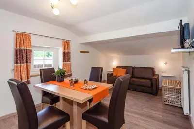 a dining room and living room with a table and chairs at Merlhof in Fiè