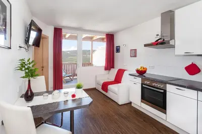 a kitchen and living room with a couch and a table at Merlhof in Fiè