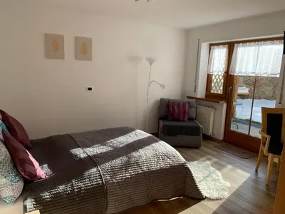 a bedroom with a bed and a chair and a window at Obereggen - Anna in Eggen