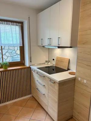 a kitchen with white cabinets and a sink and a window at Obereggen - Anna in Eggen