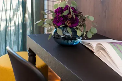a vase with purple flowers on a table next to a book at ANTON Dolomites Hideaway in Brunico