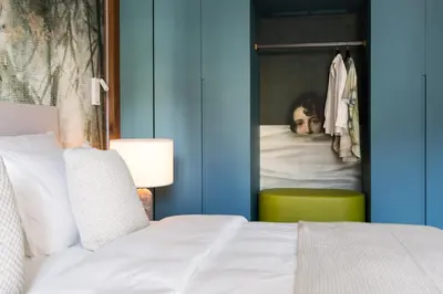 a bedroom with a white bed and a green chair at ANTON Dolomites Hideaway in Brunico