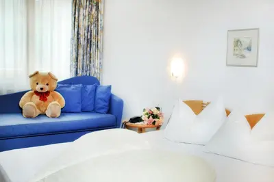 a teddy bear sitting on a blue couch in a hotel room at Hotel Rierhof in Chiusa