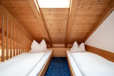 two beds in a small room with wooden ceilings at Hotel Rierhof in Chiusa