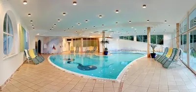 a large swimming pool in a building with chairs around it at Hotel Rierhof in Chiusa