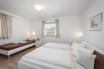 a white bedroom with two beds and a window at Panorama Residence Schlossblick in Rodengo