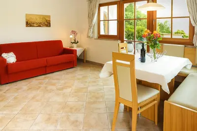 a living room with a red couch and a table at Weingut & Apartments Weitgruber Raffeis in Merano