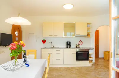 a kitchen with white cabinets and a table with flowers at Weingut & Apartments Weitgruber Raffeis in Merano