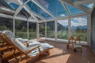 a room with two beds and chairs and a large window at Hotel Bad Salomonsbrunn in Anterselva di Mezzo