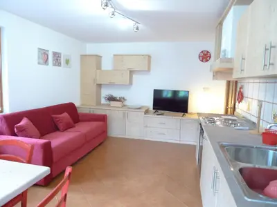 a living room with a red couch in a kitchen at Casa Sorarù in Rocca Pietore