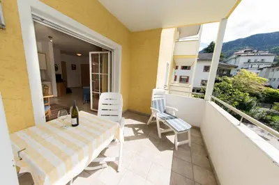 a patio with a table and chairs on a balcony at Apartments Villa Majense in Merano
