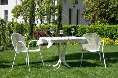 a table with wine glasses and two chairs in the grass at Apartments Villa Majense in Merano