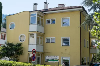 a yellow building with a sign in front of it at Apartments Villa Majense in Merano