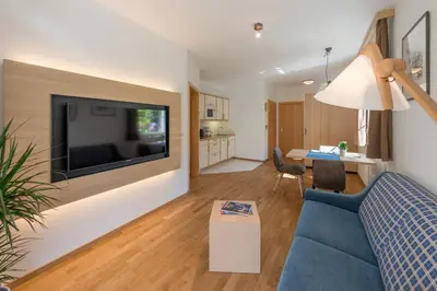 a living room with a blue couch and a tv on a wall at Apartments Villa Majense in Merano