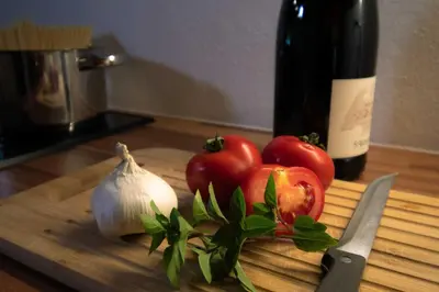 a cutting board with tomatoes and garlic and a bottle of wine at Melanies Guesthouse 2 Zimmerwohnung in Caldaro