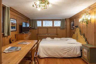 a bedroom with a bed and a wooden table at FALORIA Studio Apartment in Cortina dʼAmpezzo