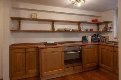 a kitchen with wooden cabinets and a stove at FALORIA Studio Apartment in Cortina dʼAmpezzo